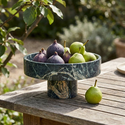 Green marble pedestal fruit bowl filled with figs and pears on an outdoor wood garden table