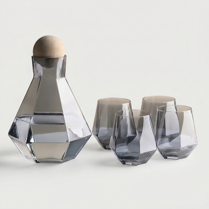 Set of geometric glass carafe and tumblers on a light background