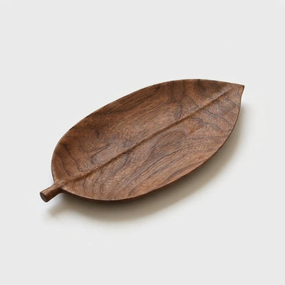 Small elliptical walnut leaf tray with a carved center vein on a light background