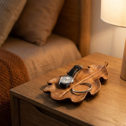 Lobed walnut leaf tray holding a wristwatch and silver bangle on a wooden nightstand