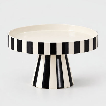 Black and white striped pedestal tray with a white interior shown at an angle on a plain light background