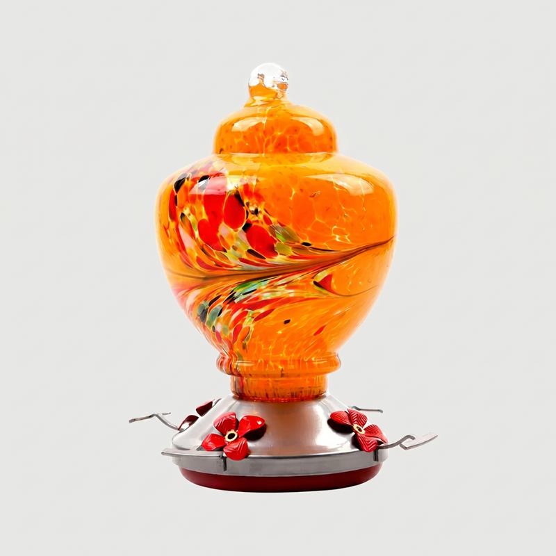 Orange handblown glass hummingbird feeder on white background