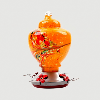 Orange handblown glass hummingbird feeder on white background