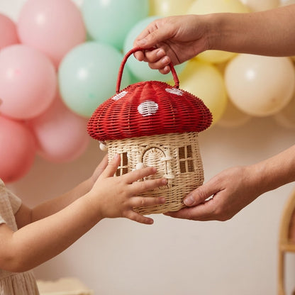 Red mushroom basket being handed to a child at a birthday party