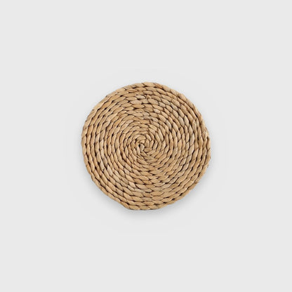 Single flat golden-tan coiled woven wall basket on a plain light gray background