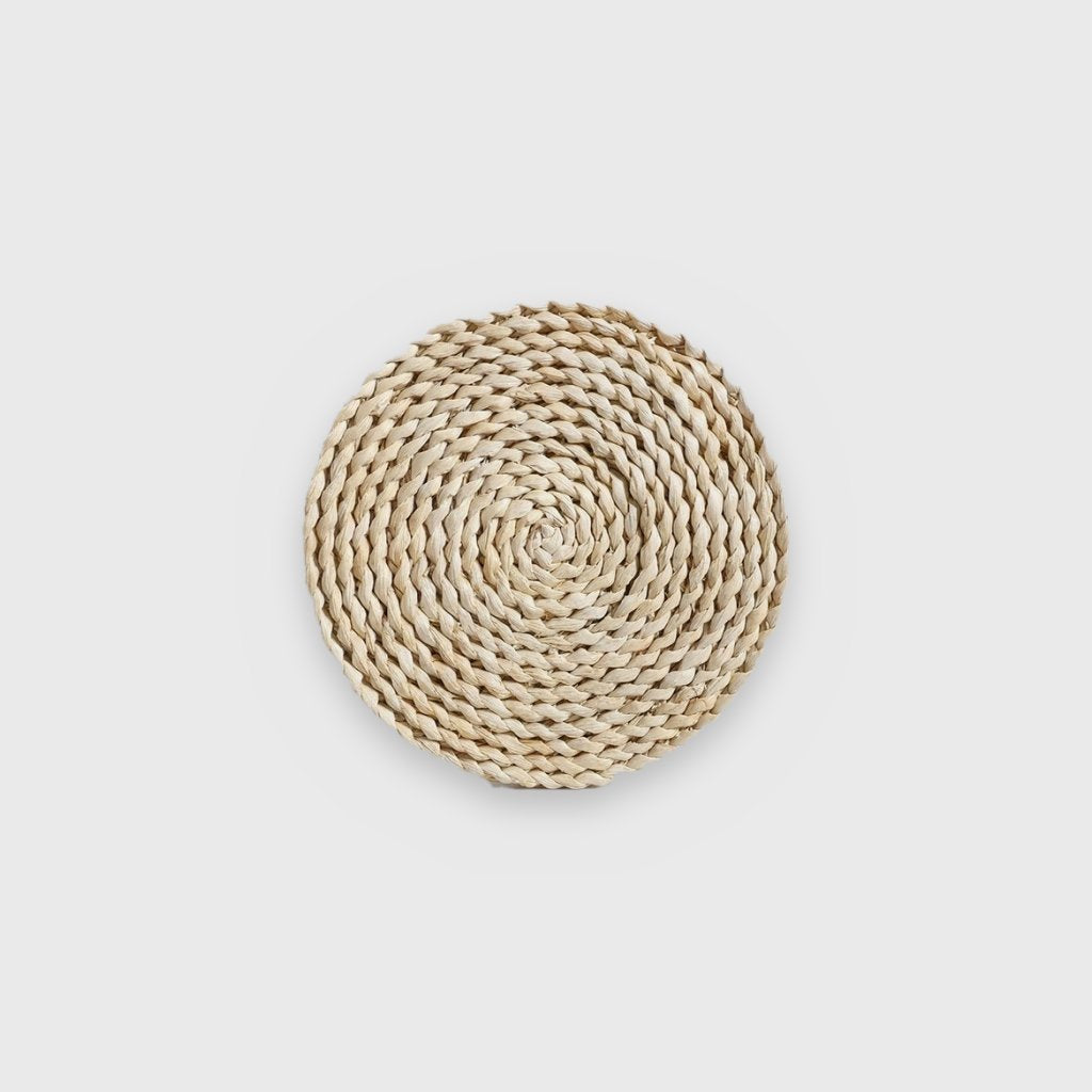 Single small flat pale cream coiled seagrass wall basket on a plain light gray background