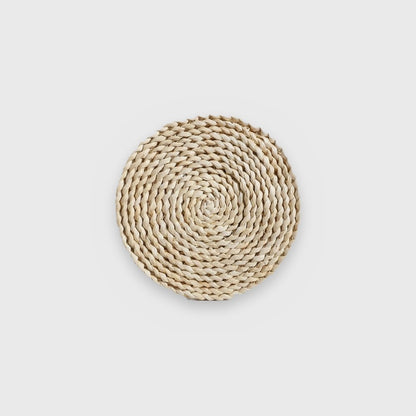 Single small flat pale cream coiled seagrass wall basket on a plain light gray background