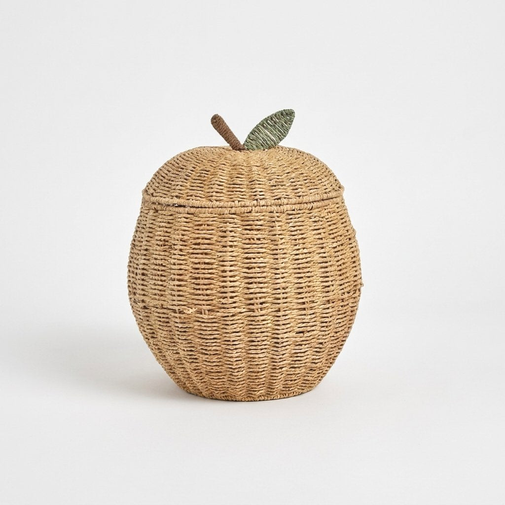 Apple-shaped woven rattan lidded basket with a brown stem and a green leaf on a light background
