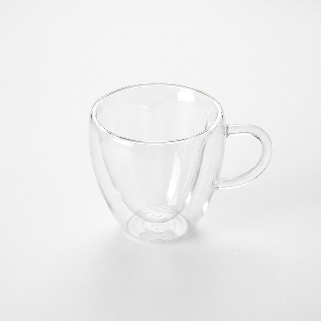Small empty heart-shaped glass mug on a plain white background