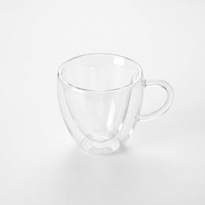 Small empty heart-shaped glass mug on a plain white background