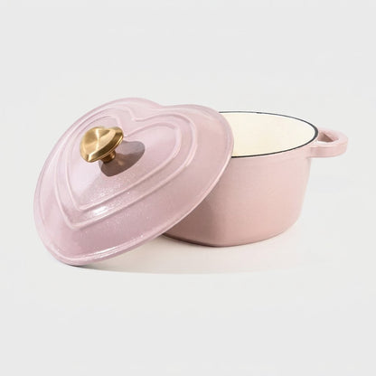 Studio product shot of the pink heart-shaped enamel pot on a plain background, lid propped against the empty pot showing the cream interior and gold heart knob