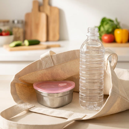 Heart-Shaped Stainless Steel Food Container packed in a canvas tote bag next to a water bottle on a kitchen counter