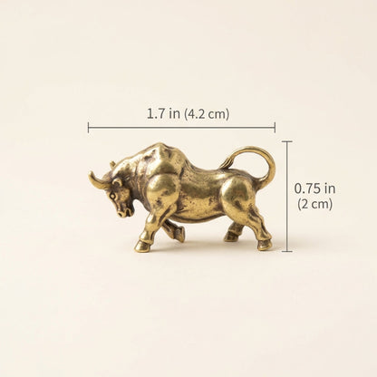 Brass bull figurine with measurements on a beige background