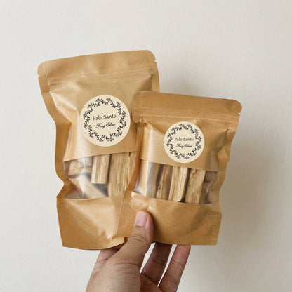 Two brown paper packages with labels held by a hand against a light background