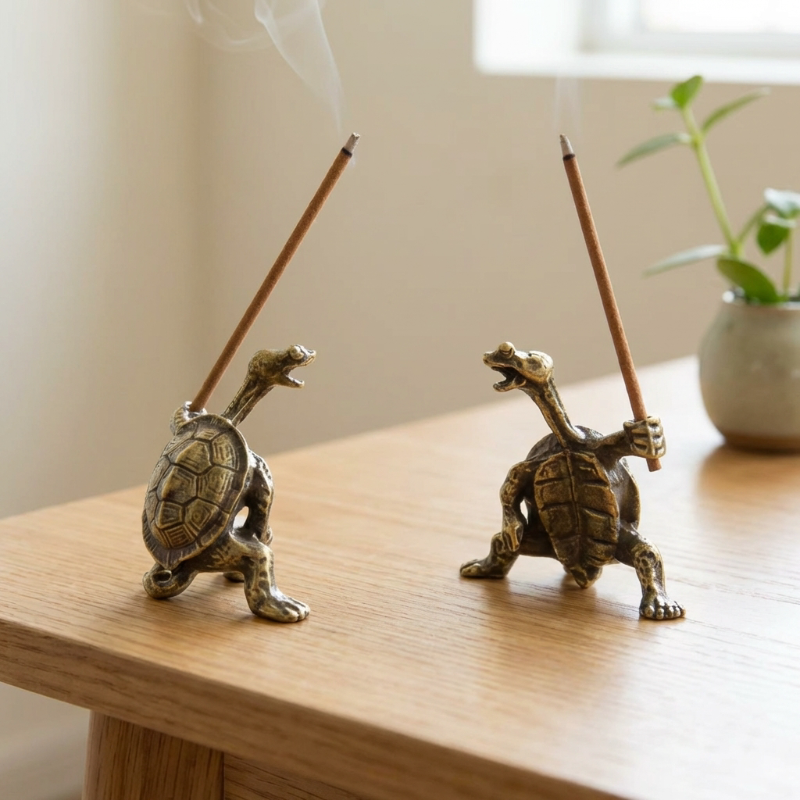 Two turtle incense holders styled on wood surface with plant