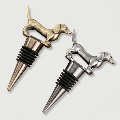 Two dachshund shaped bottle stoppers, one gold and one silver, on a light gray background.