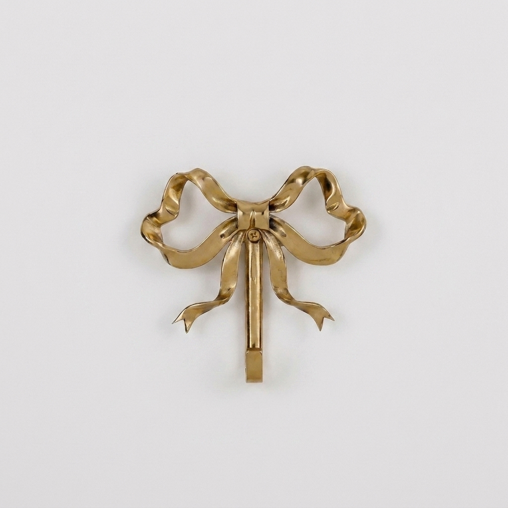 Small gold bow-shaped wall hook on a plain studio background