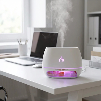 White essential oil diffuser with colorful LED lights on a desk next to a laptop.