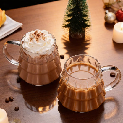 Two tree-shaped glasses with hot cocoa and coffee on a wood table with mini Christmas tree decor
