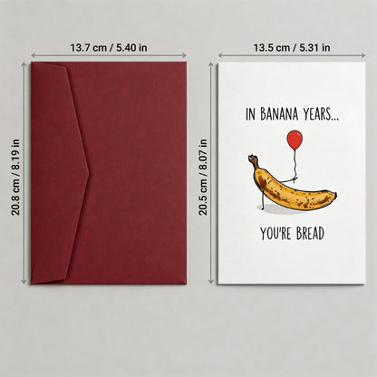 Red envelope and greeting card with banana illustration and text on a gray background