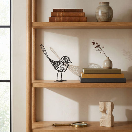 Iron bird sculpture on wooden bookshelf with books and decor