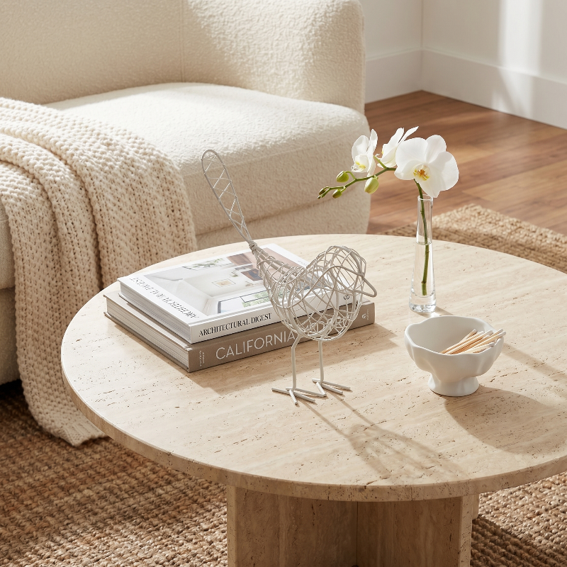 Iron bird sculpture on round coffee table in neutral living room