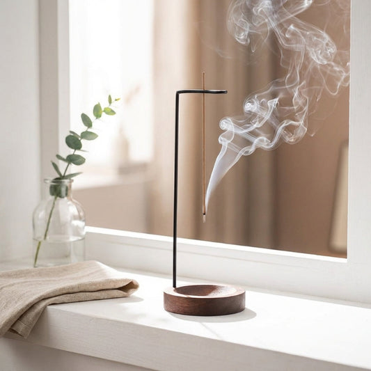 Wooden incense burner with smoke on a windowsill with a plant and towel in the background
