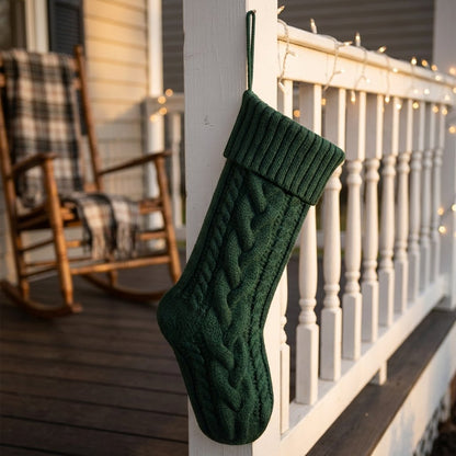 Green knit Christmas stocking hanging from a porch post strung with string lights