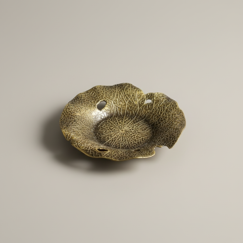 Decorative bronze leaf-shaped object on a beige background