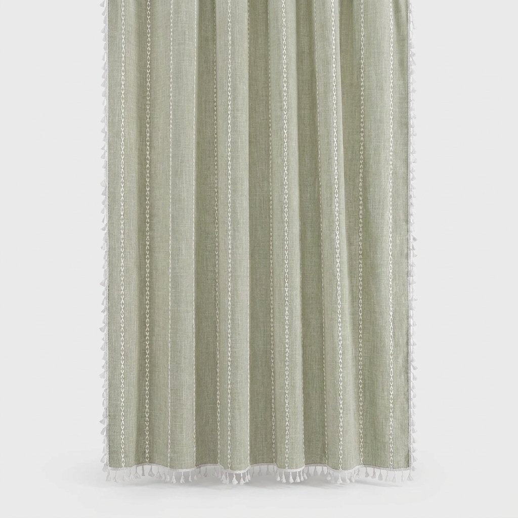Sage green linen shower curtain with thin white stitched vertical stripes and white tassels on a light grey background