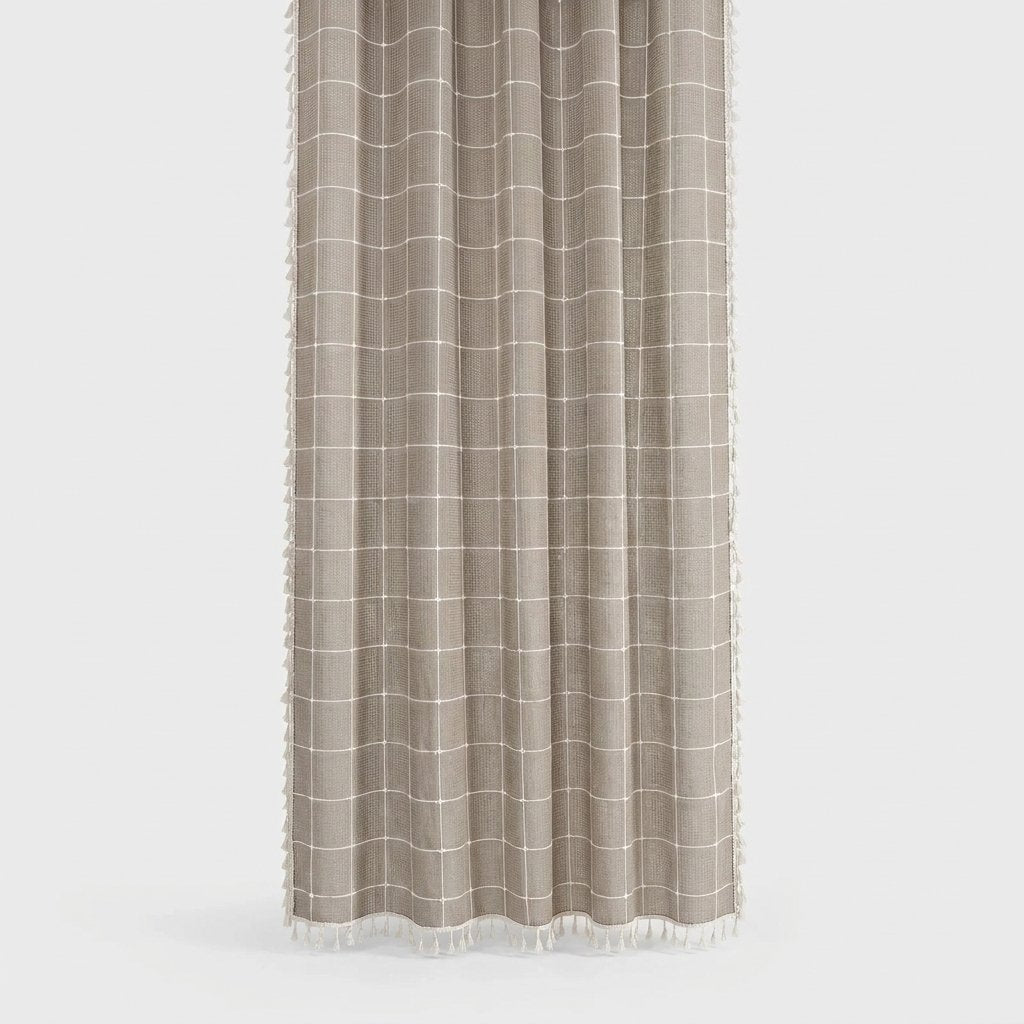 Taupe windowpane linen shower curtain with a thin cream grid and small cream tassels along the hem and sides on a light grey background
