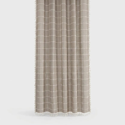 Taupe windowpane linen shower curtain with a thin cream grid and small cream tassels along the hem and sides on a light grey background