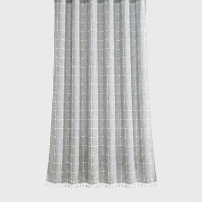 Heathered light gray windowpane linen shower curtain with a white grid and small white tassel hem on a light grey background