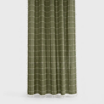 Olive green windowpane linen shower curtain with a cream grid and white tassels on the hem and sides on a light grey background