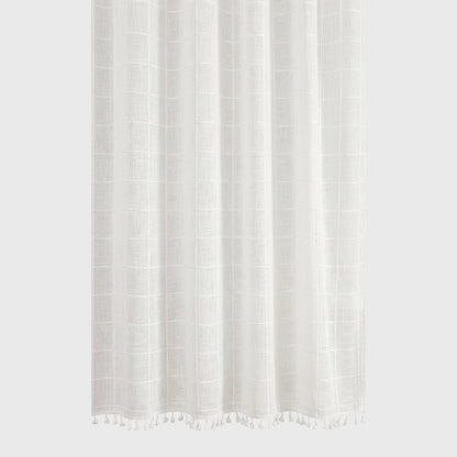 Close-up of a white semi-sheer windowpane linen shower curtain with a white tassel hem on a light grey background