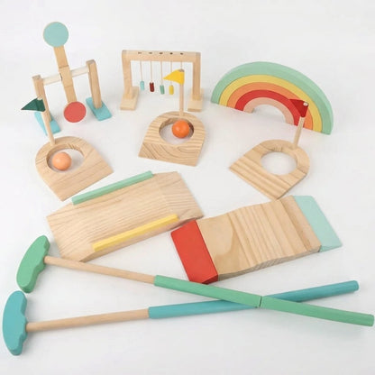 Full wooden mini golf set laid out on a white background, including the spinner post, bead-frame obstacle, rainbow arch, three flagged holes, ramp pieces, and two putters