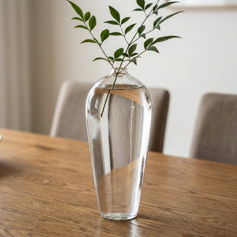 Lucia hand-blown clear glass vase with leafy branch on dining table