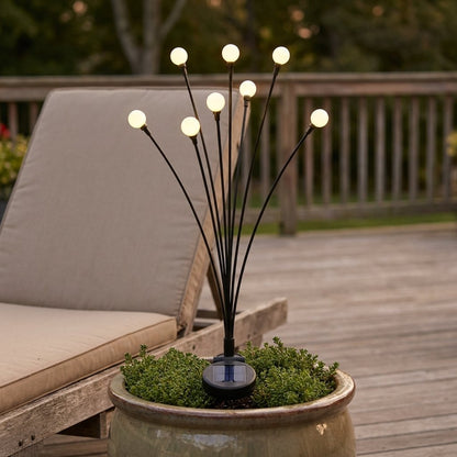 Lit solar garden light in a ceramic planter on a wood deck beside a cushioned lounge chair