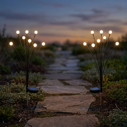 Two lit solar garden lights flanking a flagstone path through low groundcover at sunset