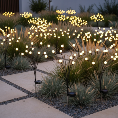 Decorative outdoor lights in a garden setting with grasses and a pathway.