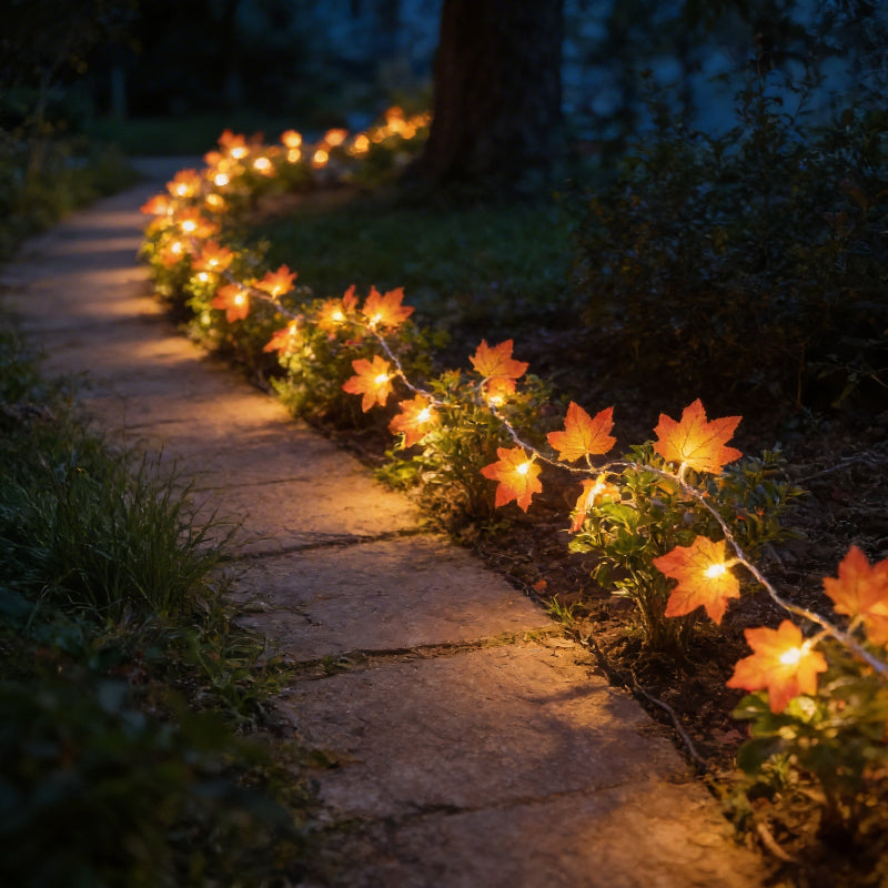 Decorative string lights with leaf design on a stone pathway at night.