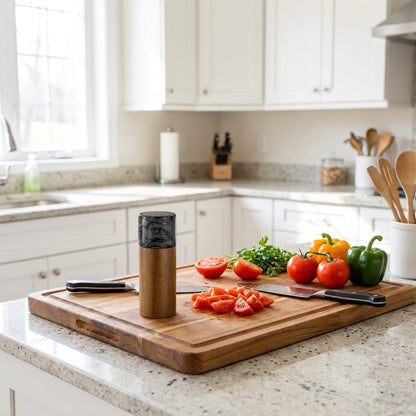 Black marble-topped acacia wood mill on a cutting board with chopped tomatoes, peppers, and herbs