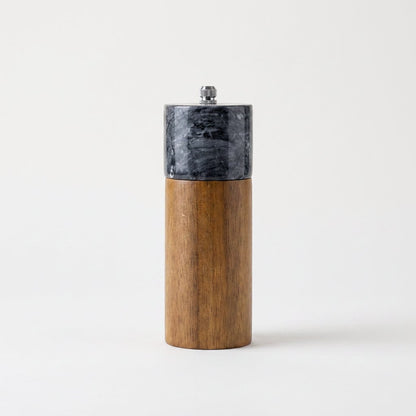 Black marble-topped acacia wood top grinder mill with a silver knob on a white studio background