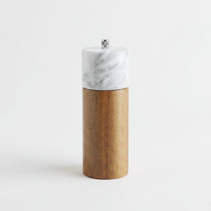 White marble-topped acacia wood top grinder mill with a silver knob on a white studio background