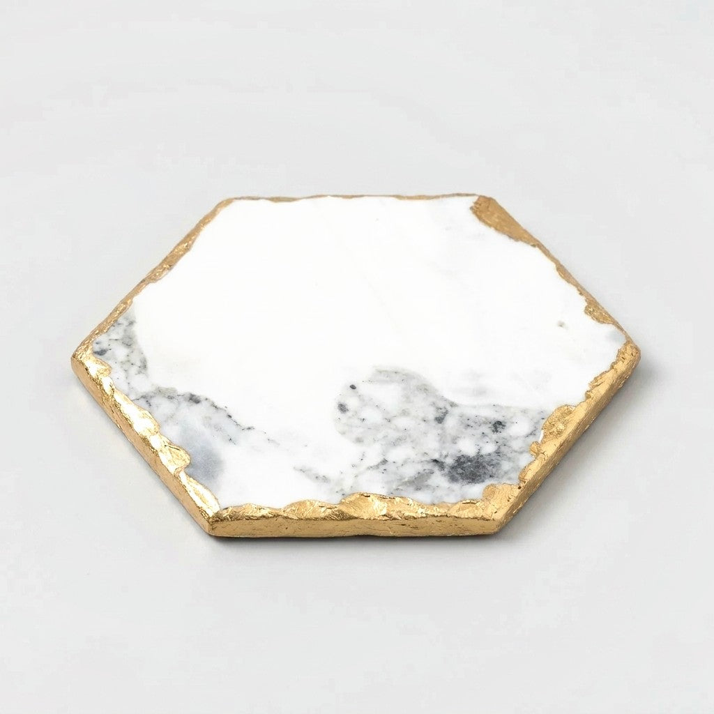 Large hexagonal white marble coaster with grey marbling and gold edging on an off-white background