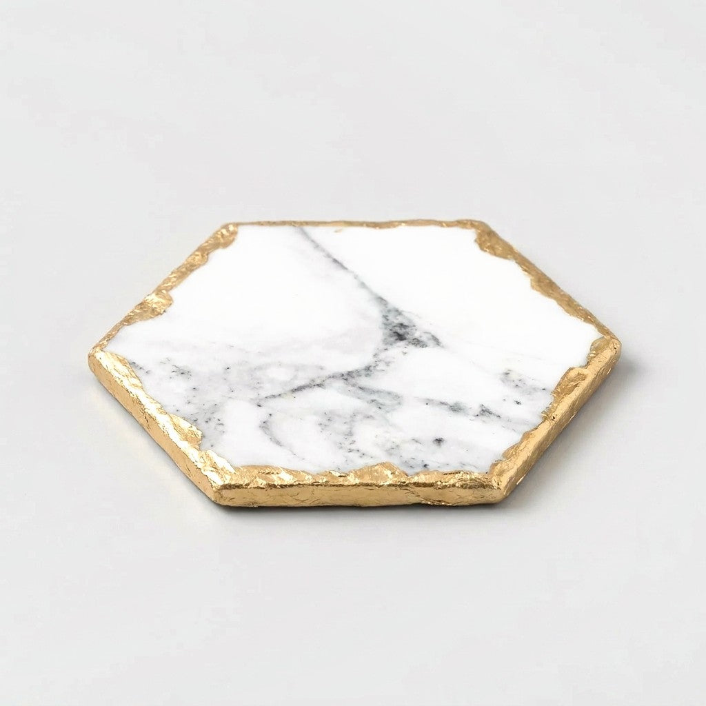 Medium hexagonal white marble coaster with grey veining and gold edging on a light grey background