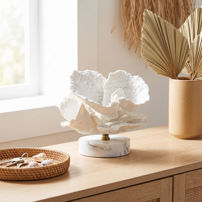 White marble coral sculpture on a console table beside books