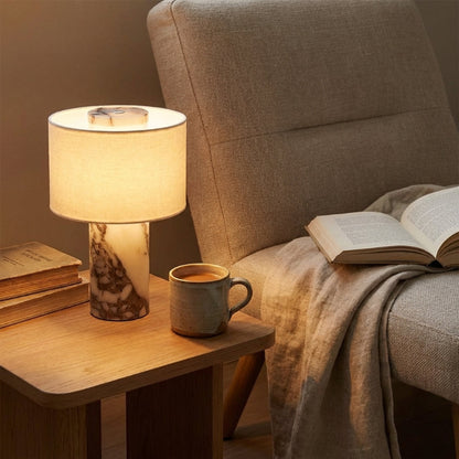 Cozy living room scene with a lamp, mug, and book on a side table next to a sofa.