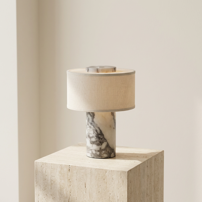 Table lamp with marble base on a light-colored pedestal against a neutral background