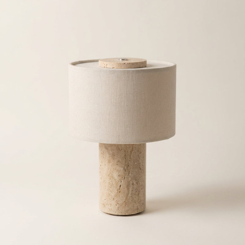 Table lamp with a beige fabric shade and stone base on a light background